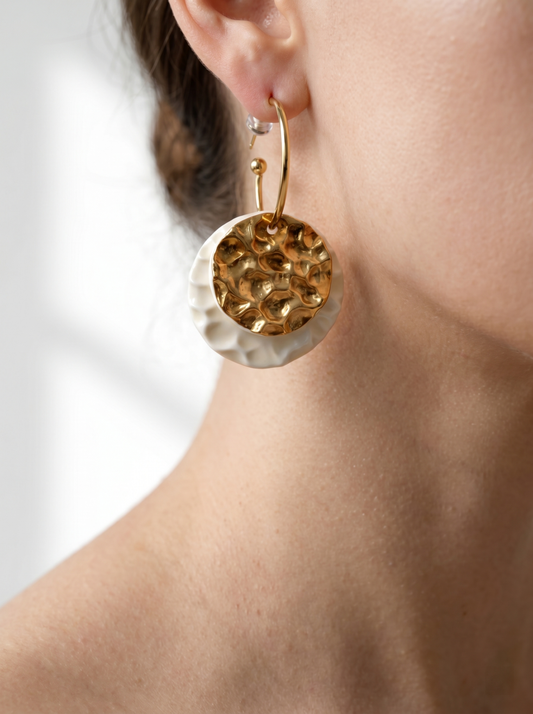 Side view of a model wearing HECROWN 006 sculptural ceramic earrings. The light highlights the hammered gold texture and the delicate white porcelain wave pattern.