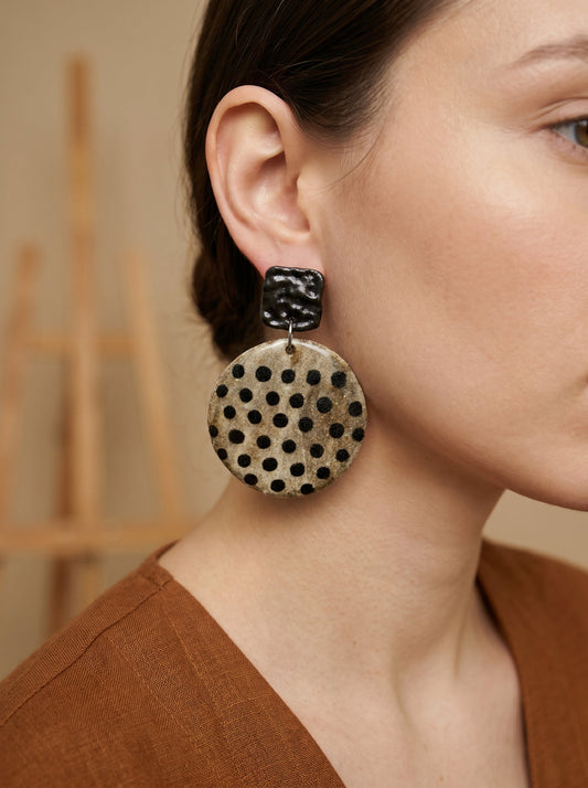 Model wearing HECROWN chunky round ceramic earrings with black speckled dots. A bold yet elegant piece of wearable art, ideal for a unique anniversary gift.