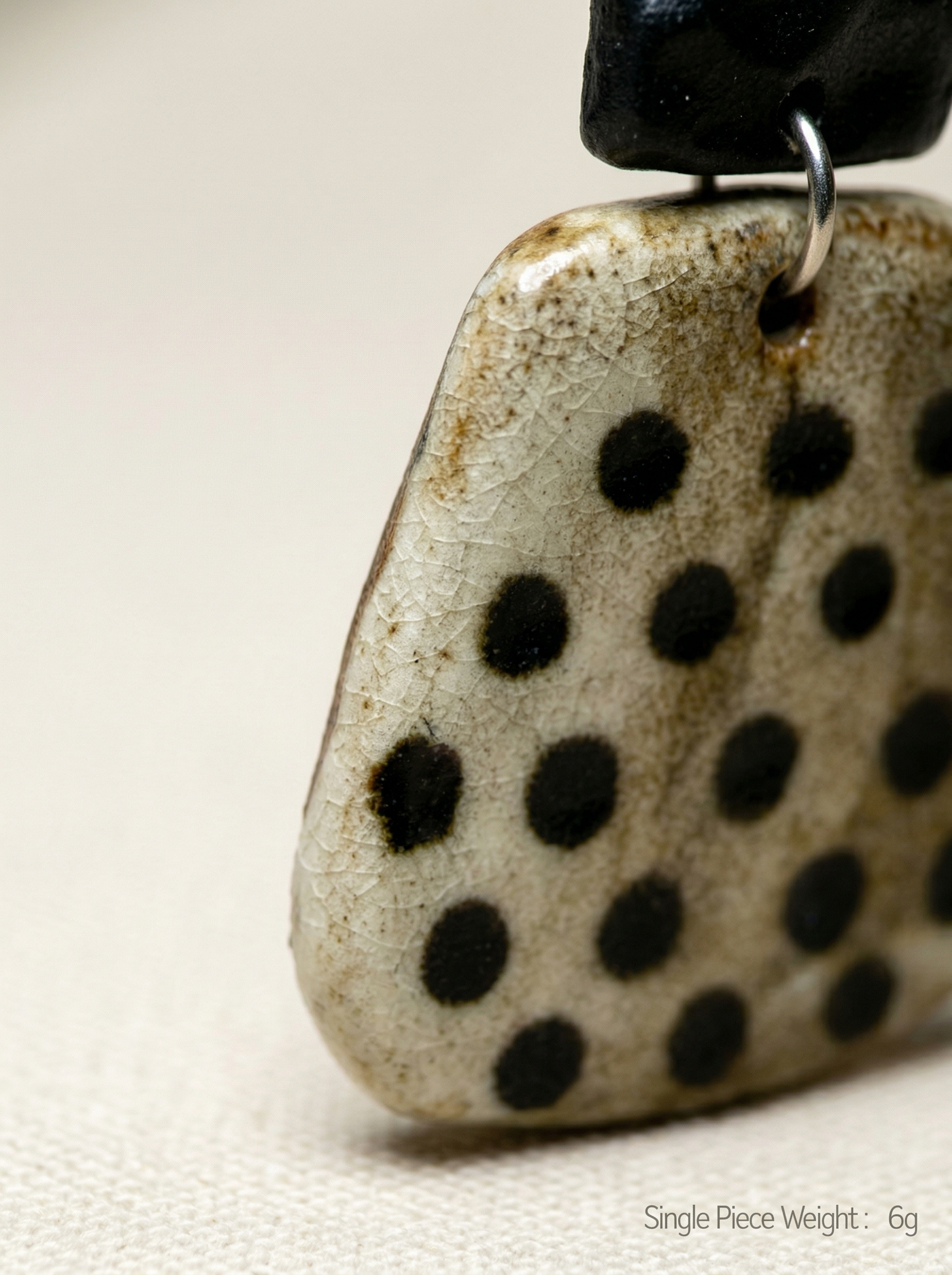 Extreme macro close-up of a HECROWN speckled ceramic earring, revealing the intricate ice crackle glaze and black dots. Authentic Jingdezhen handmade jewelry details.