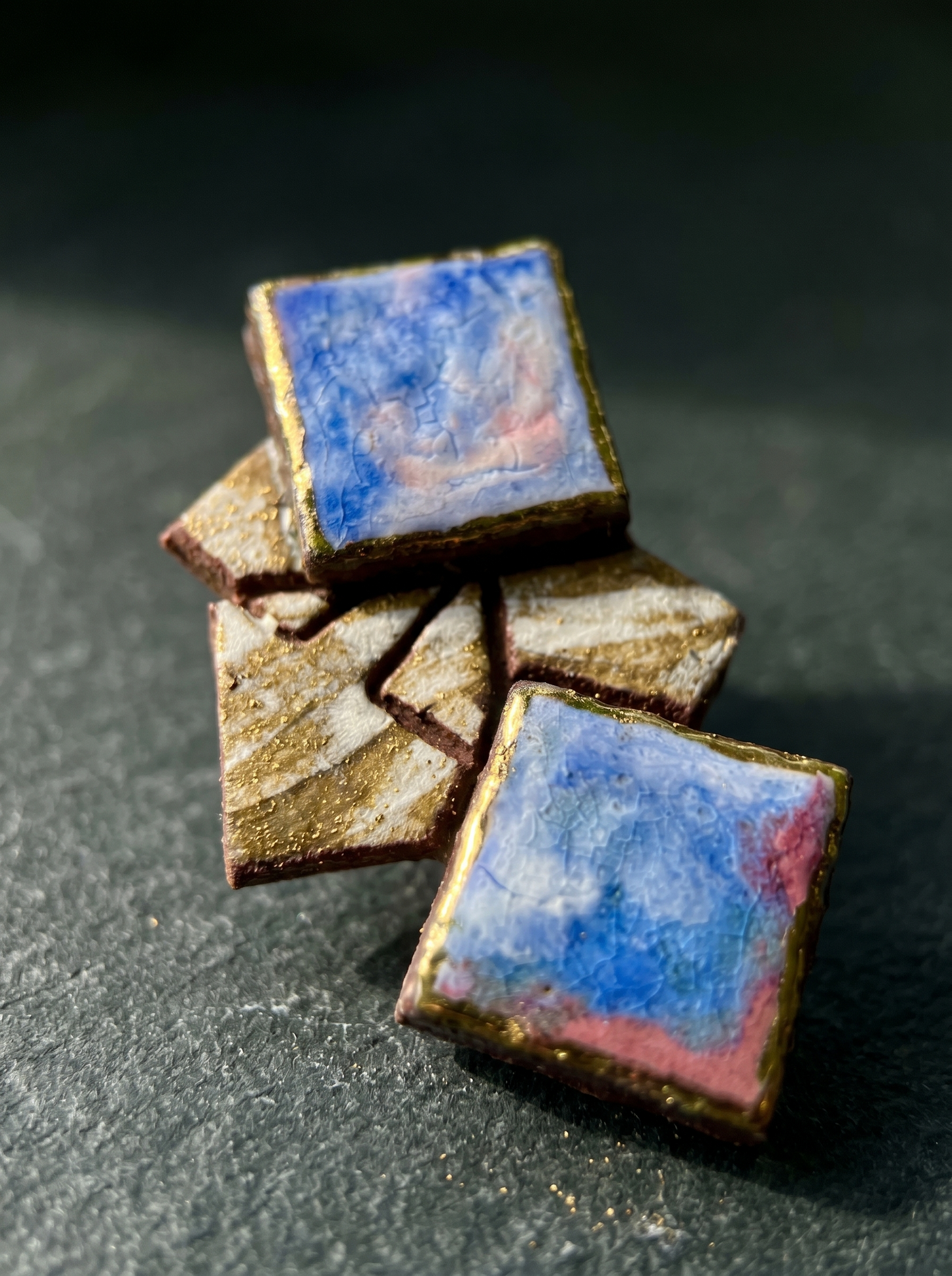 Extreme close-up of HECROWN 003 geometric ceramic earrings on a dark textured slate surface. Direct sunlight highlights the detailed crackle glaze, golden hand-painted edges, and the raw, earthy textures of the clay fragments. A testament to the sincere handcrafted quality from Jingdezhen.