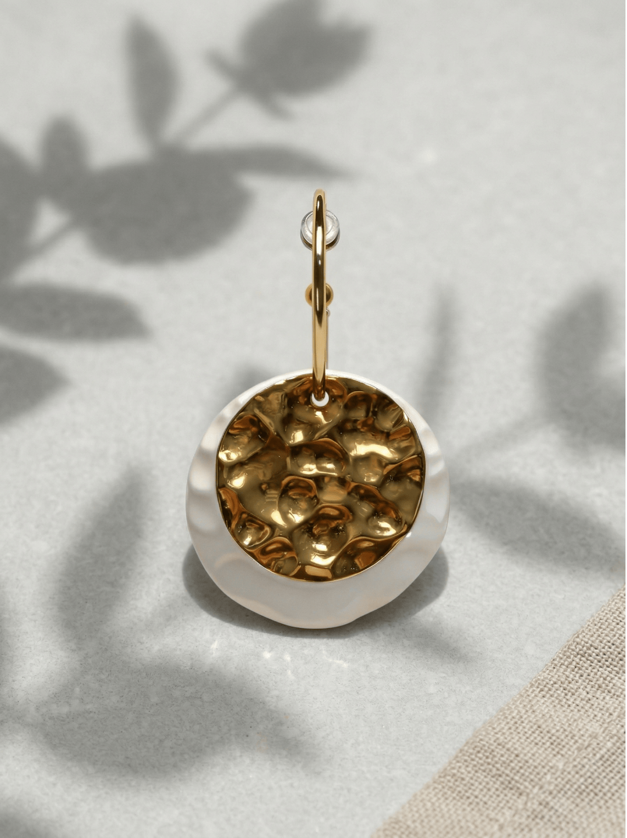 HECROWN 006 earrings on a marble table with a white tulip, captured in warm morning sunlight to highlight the realistic physical details and handmade warmth.