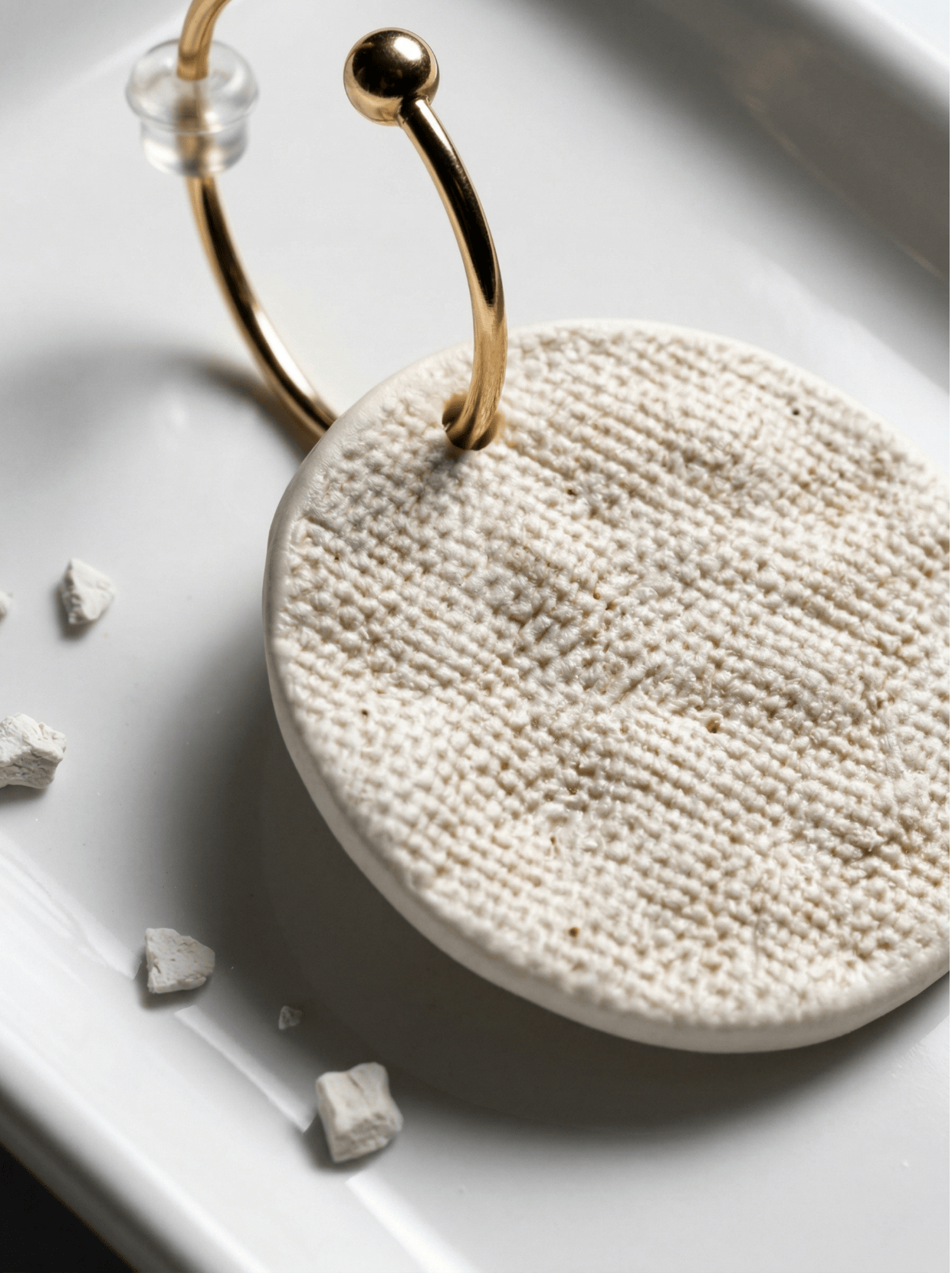 Extreme macro shot of the reverse side of HECROWN 006 earring, showing the intricate fabric-like texture of the unglazed white porcelain, emphasizing handcrafted sincerity.