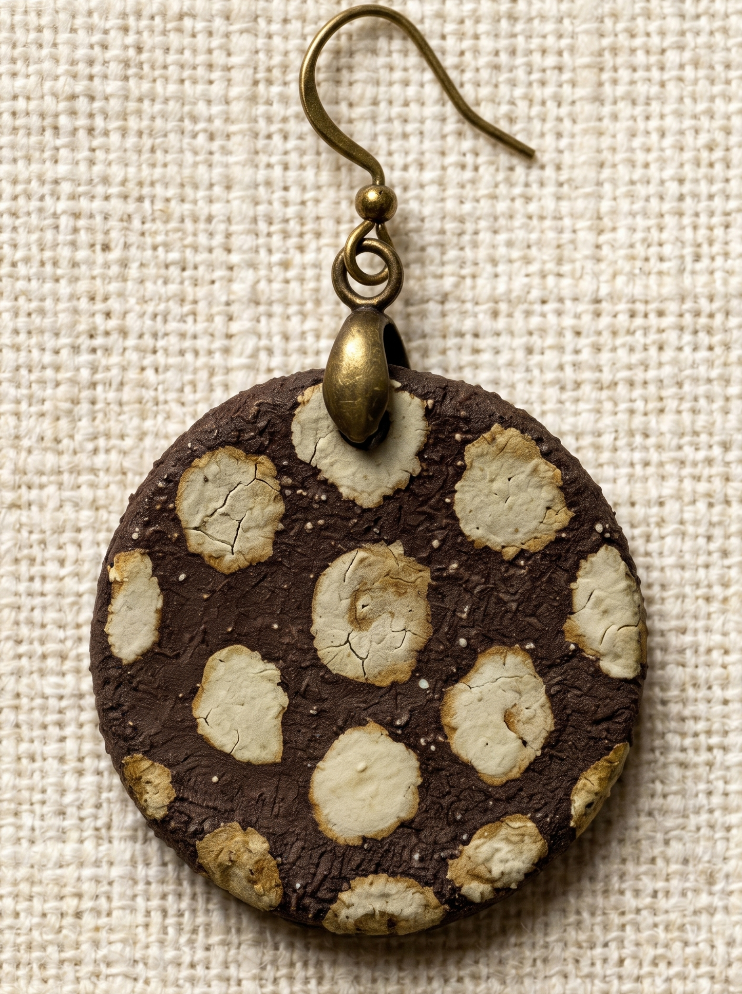 Extreme macro close-up of a HECROWN ceramic earring, highlighting the rustic brown texture and the intricate ice crackle glaze inside the beige dots. Sincere handcrafted jewelry.