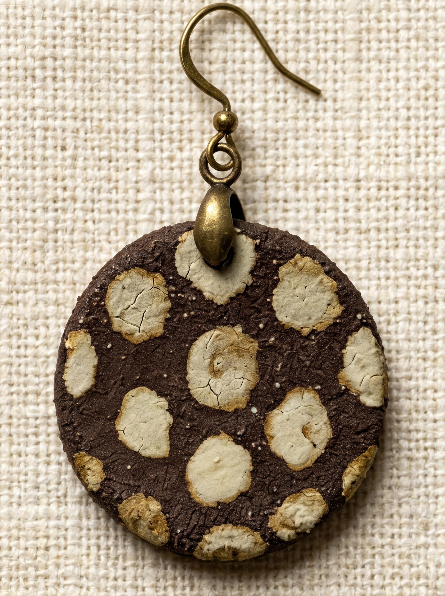 Extreme macro close-up of a HECROWN ceramic earring, highlighting the rustic brown texture and the intricate ice crackle glaze inside the beige dots. Sincere handcrafted jewelry.