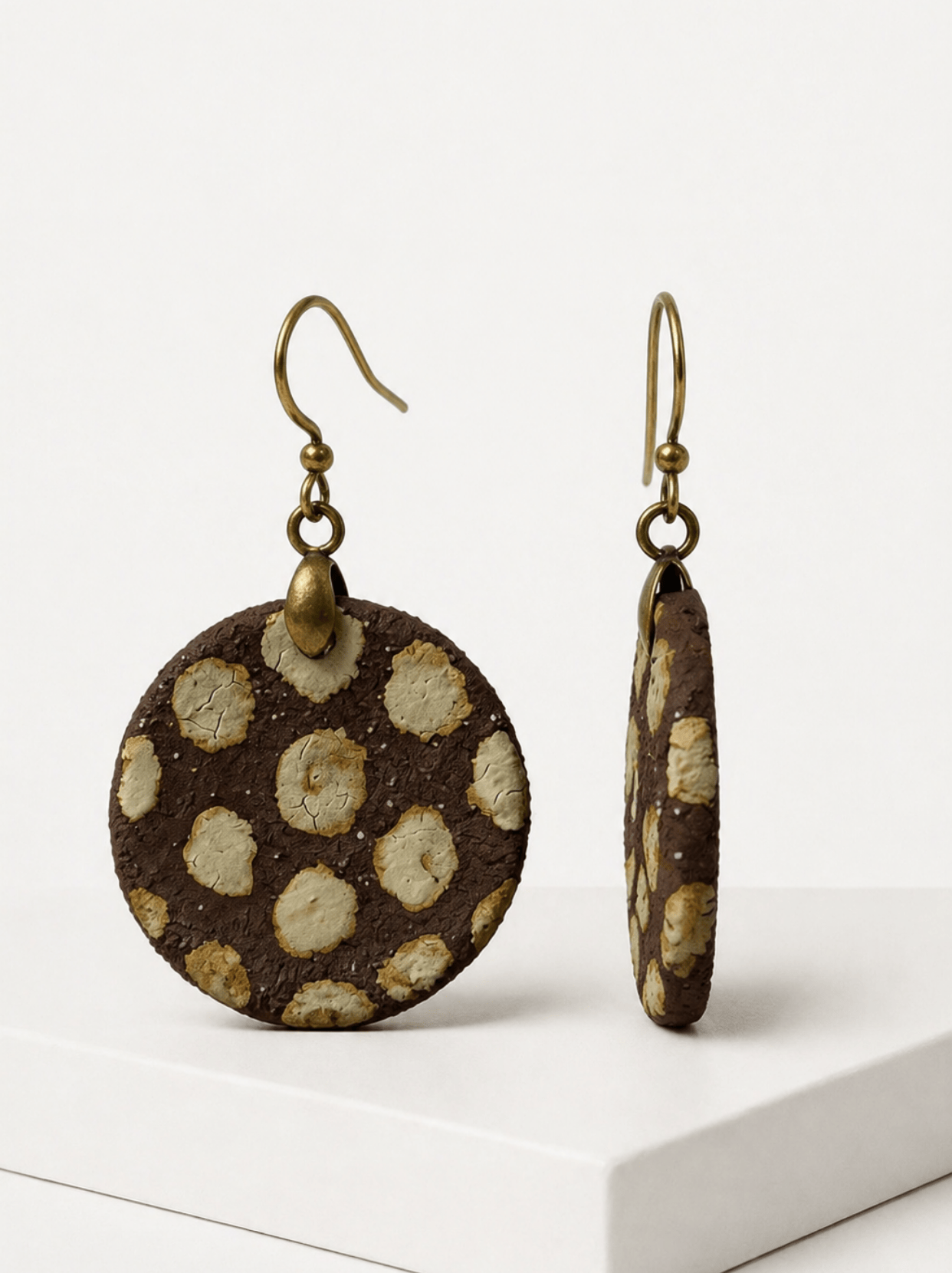 Front and side view of HECROWN brown crackle ceramic drop earrings on a white pedestal. Showcasing the raw clay thickness and raised texture of authentic handcrafted artisan jewelry.