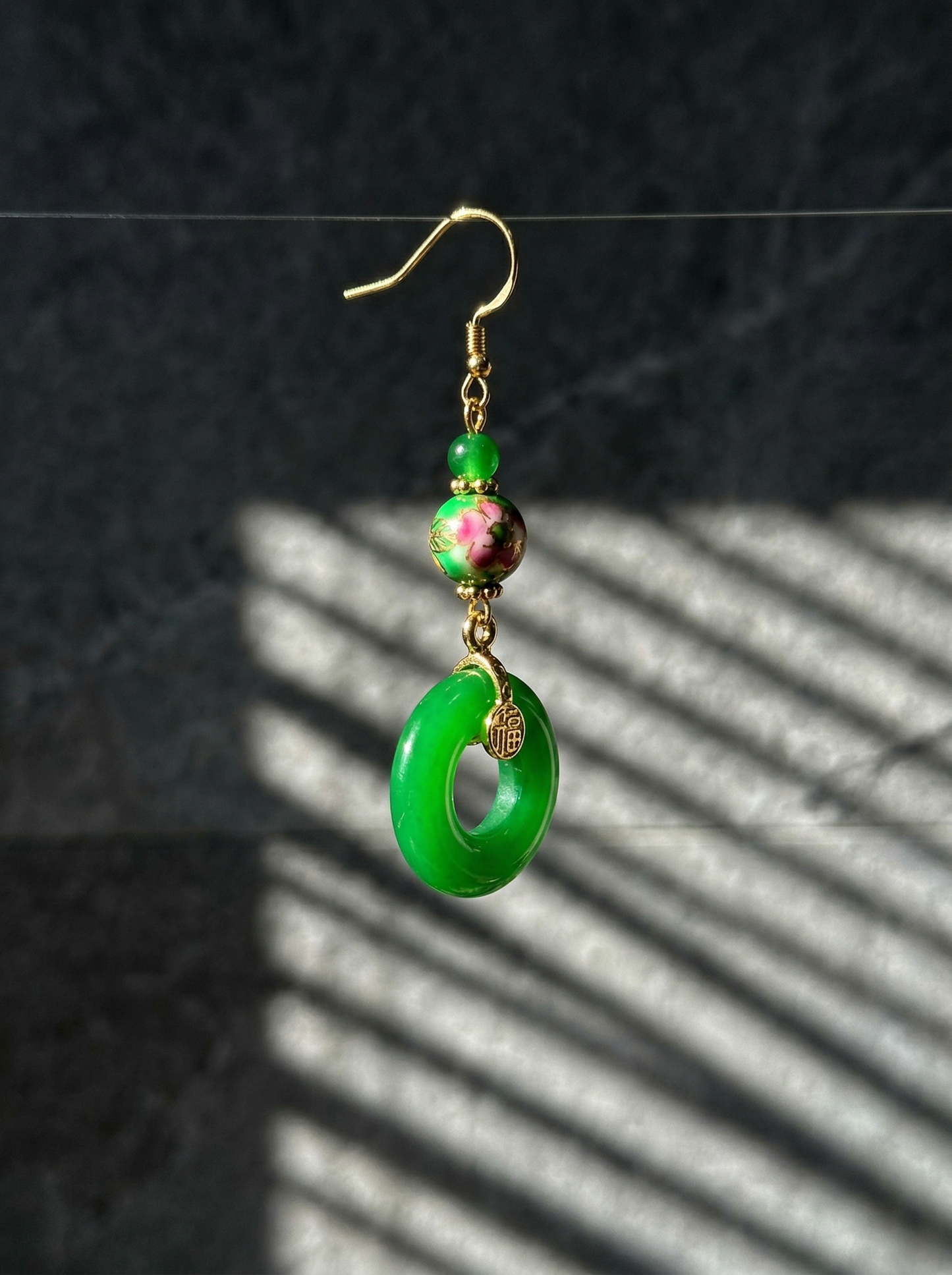 HECROWN green porcelain earrings suspended against a dark moody background. Emphasizing the vibrant green glaze of authentic Jingdezhen porcelain jewelry.