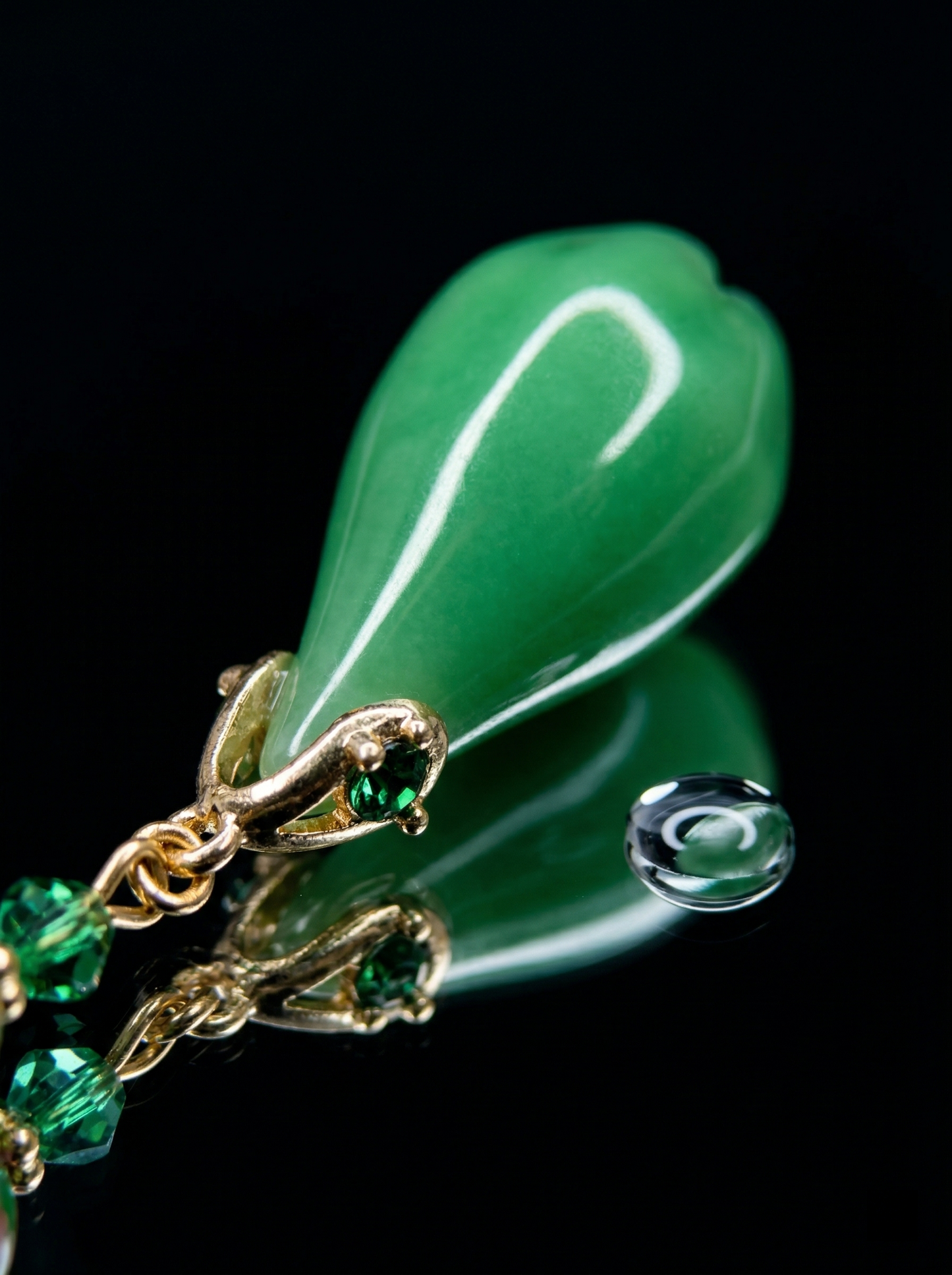 Macro close-up of a HECROWN green ceramic teardrop earring reflecting on a black surface with a water drop. Showcasing the sincere quality of Jingdezhen porcelain.