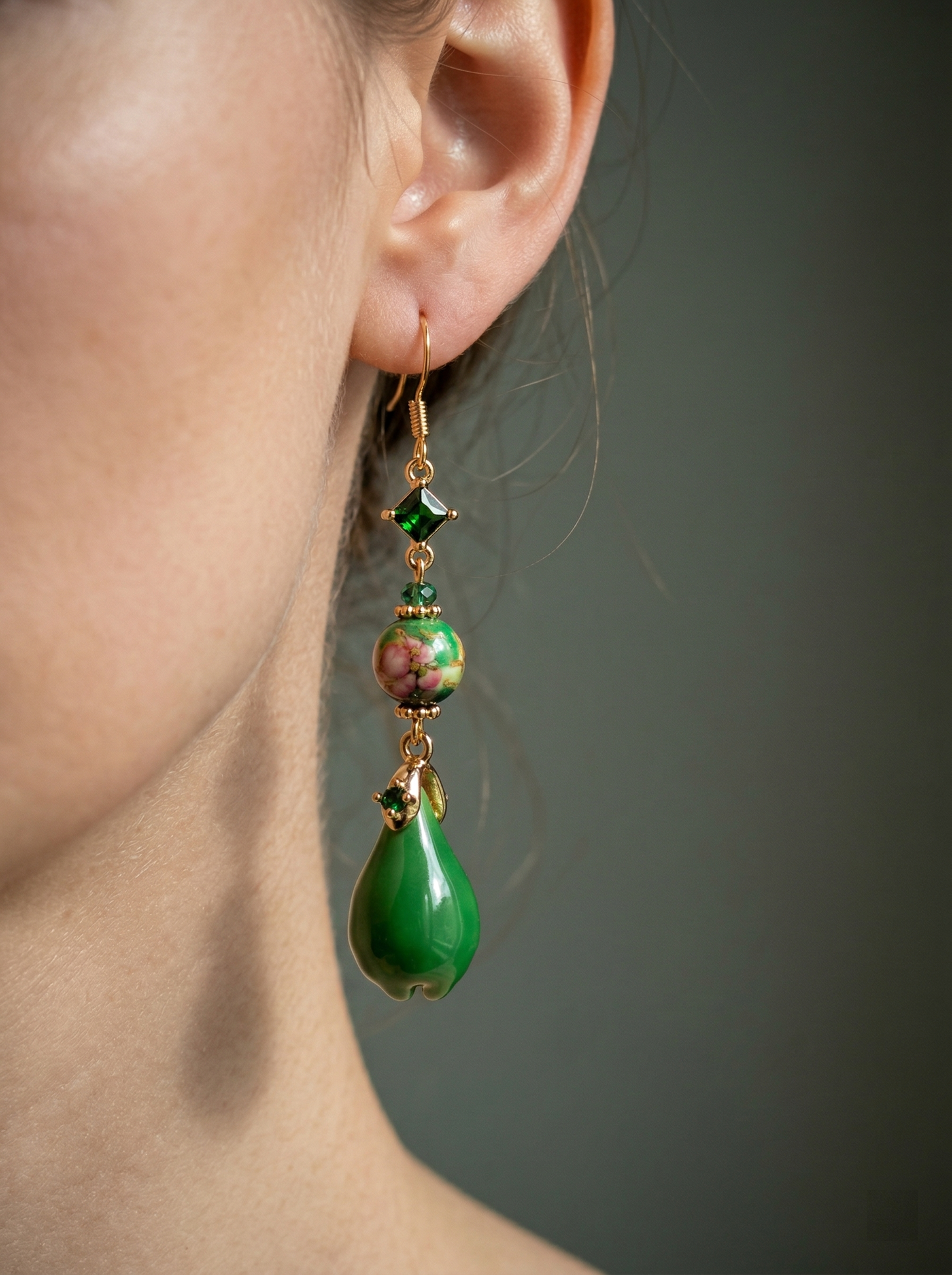 Side profile of a model wearing HECROWN long green ceramic drop earrings. Highlighting the elegant and dramatic aesthetic of artisan handcrafted jewelry.