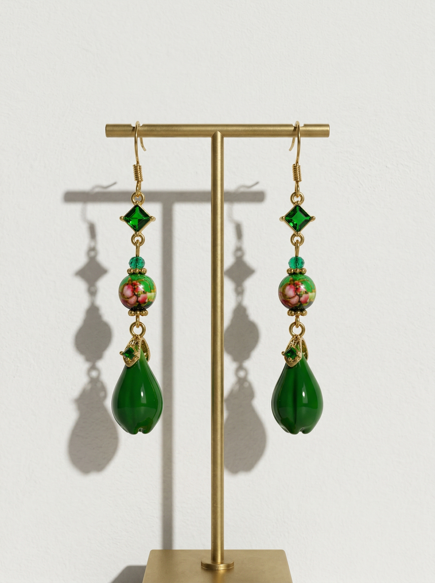 A pair of HECROWN 018 long emerald green ceramic teardrop earrings with floral beads and crystals on a gold stand. Sincere Jingdezhen handmade jewelry.