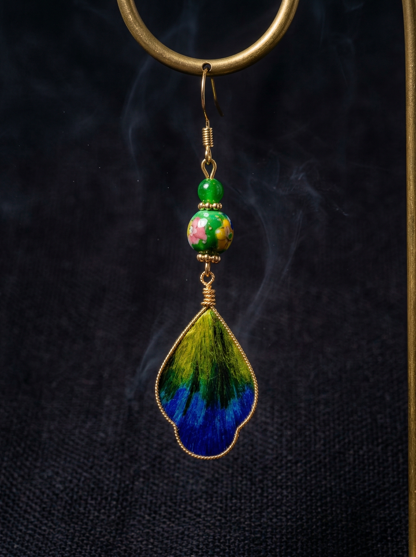 HECROWN ceramic and silk earring suspended against a dark background with zen smoke. Highlighting the sincere wabi-sabi handcrafted details.