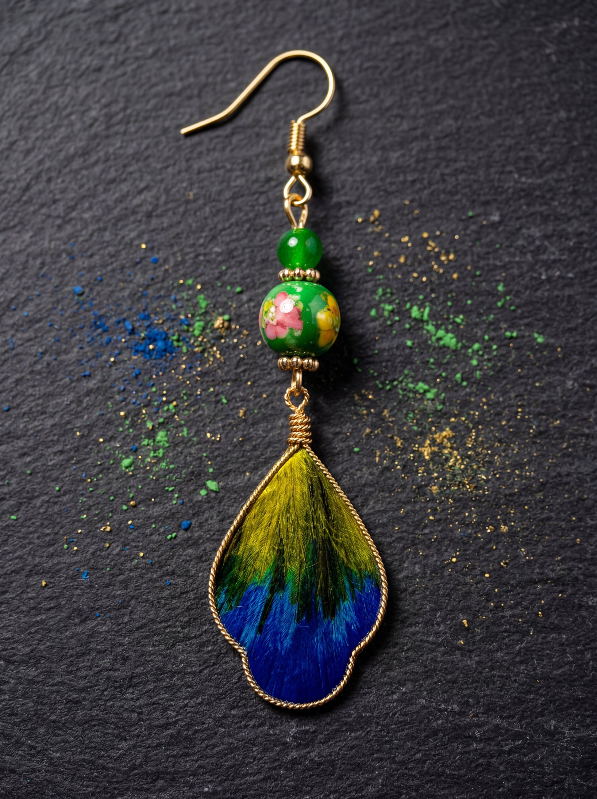 Macro close-up of the HECROWN silk and ceramic earring on a slate surface with mineral pigments. Showcasing the sincere hand-painted texture.