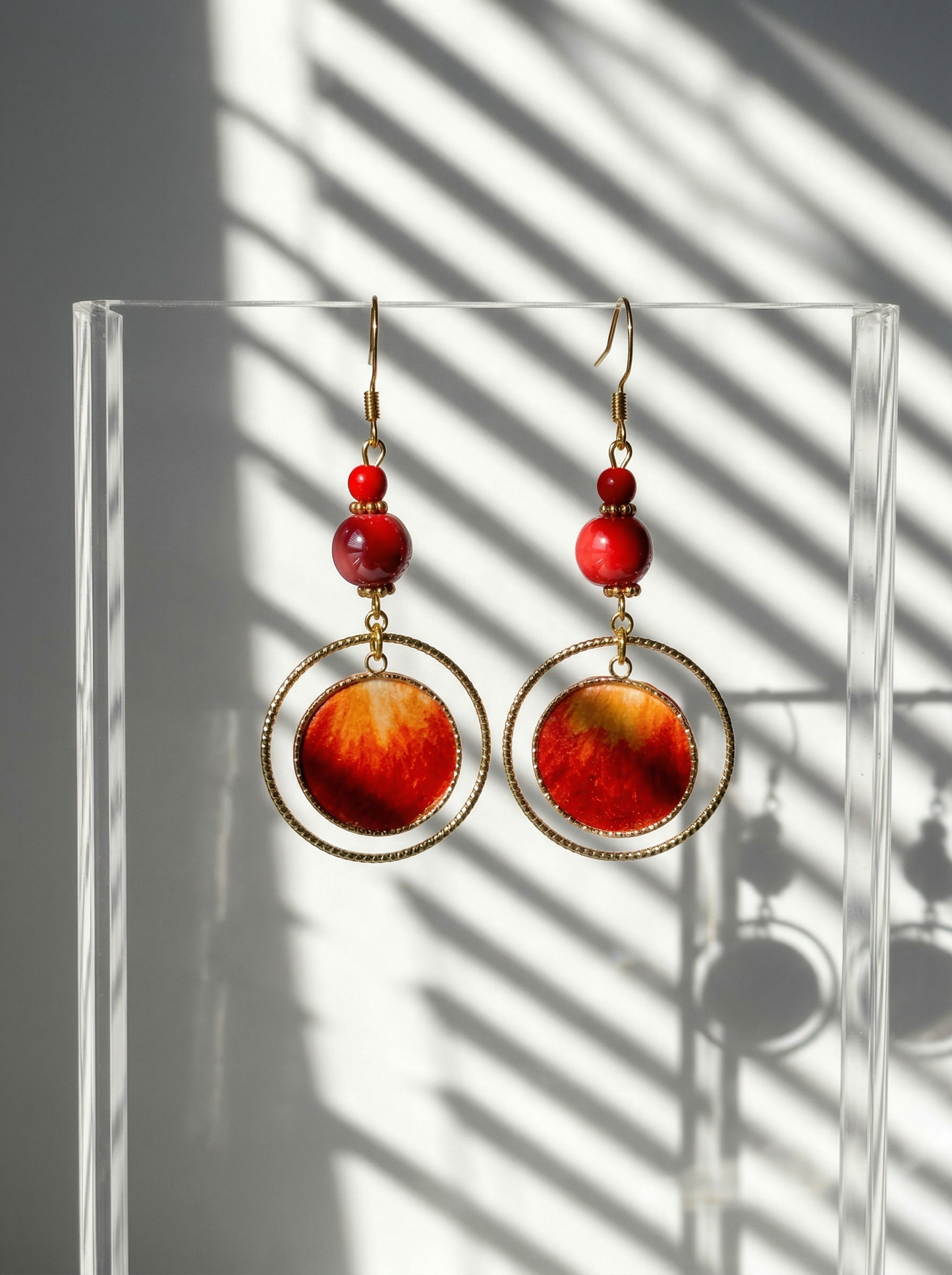 HECROWN red silk and porcelain earrings suspended on an acrylic stand with blind shadows. Showcasing the contemporary side of Jingdezhen ceramic jewelry.