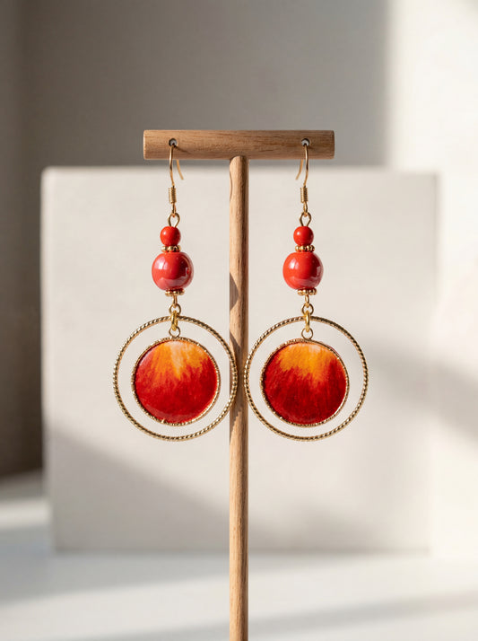 A pair of HECROWN 020 fiery red sun earrings made of ceramic and silk, displayed on a wooden stand. Sincere Jingdezhen handmade jewelry.