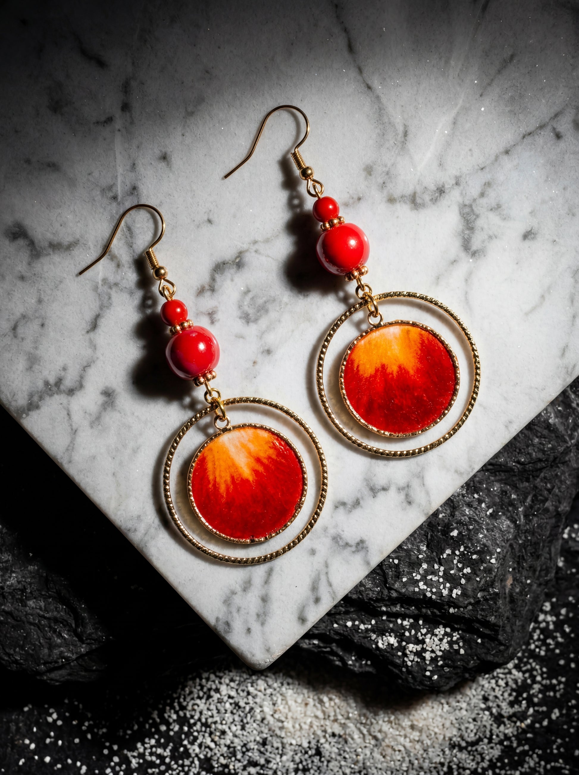 HECROWN handcrafted red silk sun earrings resting on a white marble surface with dramatic shadows. Elegant Jingdezhen ceramic art for unique gifts.