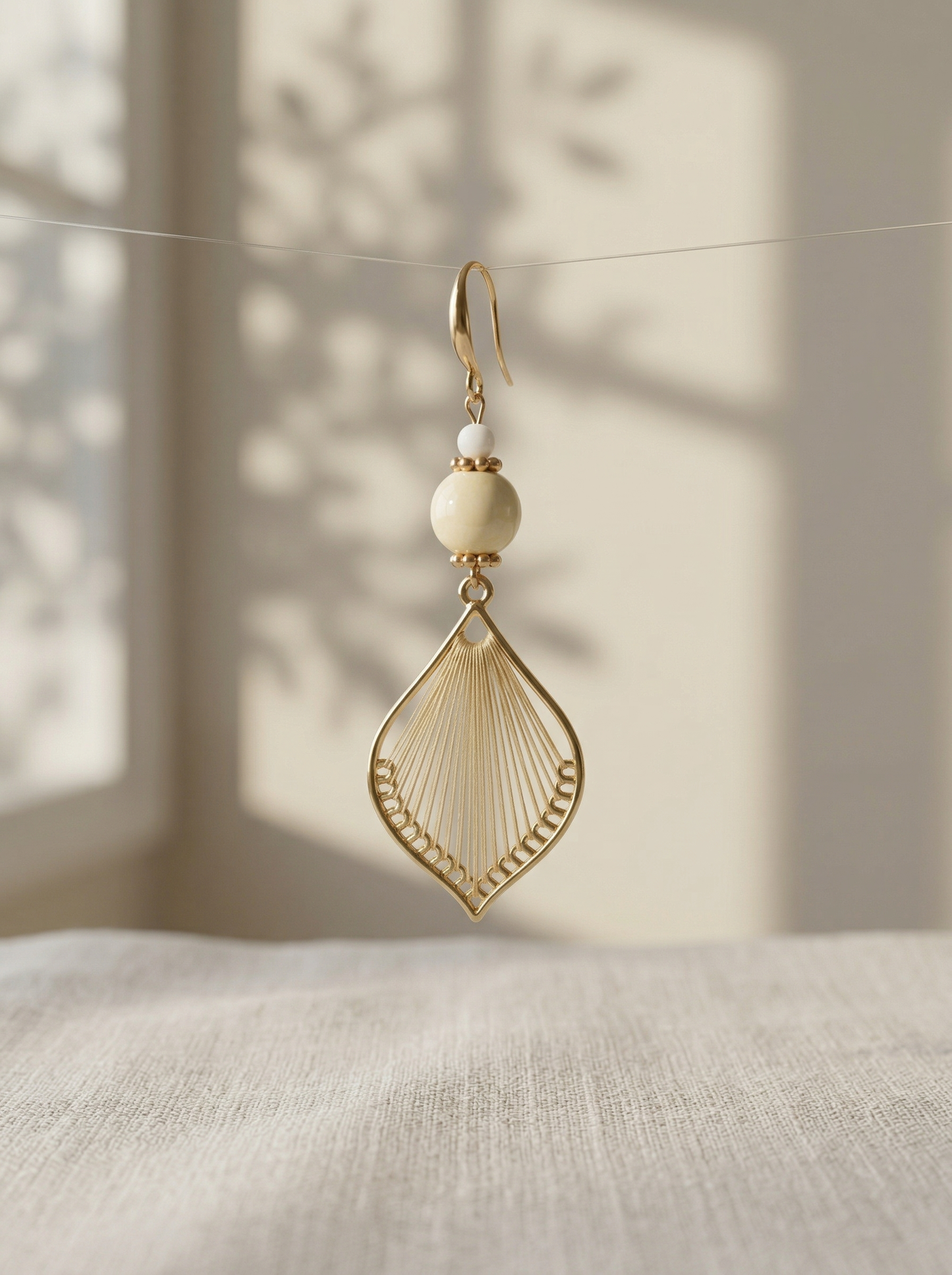 HECROWN handcrafted silk and porcelain earring hanging on a thin line with soft leaf shadows. Sincere wabi-sabi handmade jewelry.