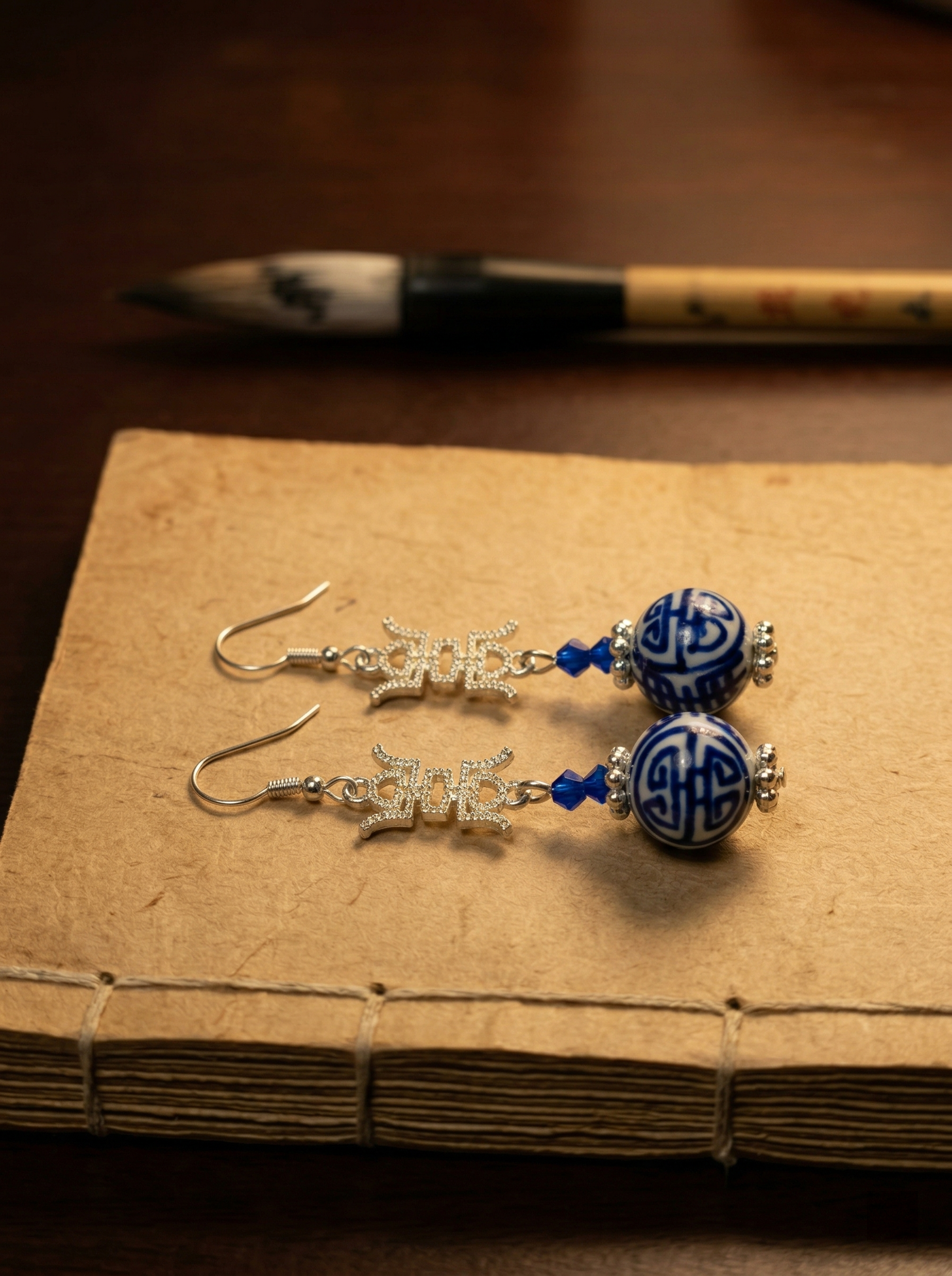 HECROWN cobalt blue floral ceramic earrings resting on soft silk with pearls. A luxurious lifestyle shot perfect for a unique Valentine's Day gift for her.