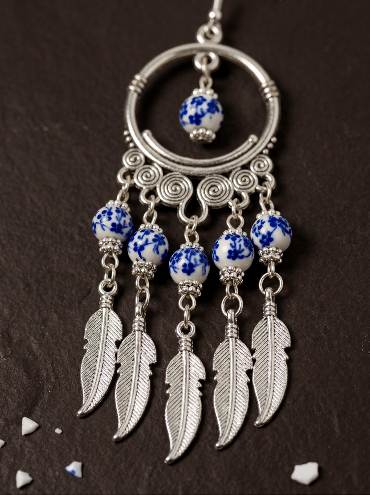 HECROWN 028 series blue phantom ceramic drop earrings hanging on a gold T-stand. Highlighting authentic handcrafted porcelain jewelry from Jingdezhen.