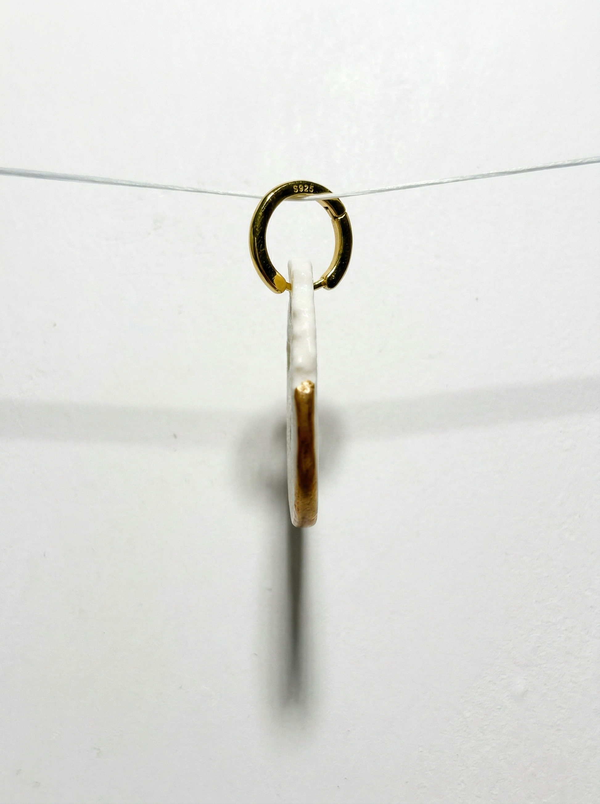 Side profile view of a handmade ceramic earring suspended on an invisible wire against a stark white background. Showcasing its surprisingly thin structure, metallic glaze edge, and S925 gold-plated hoop, proving that HECROWN statement jewelry is designed for lightweight comfort.