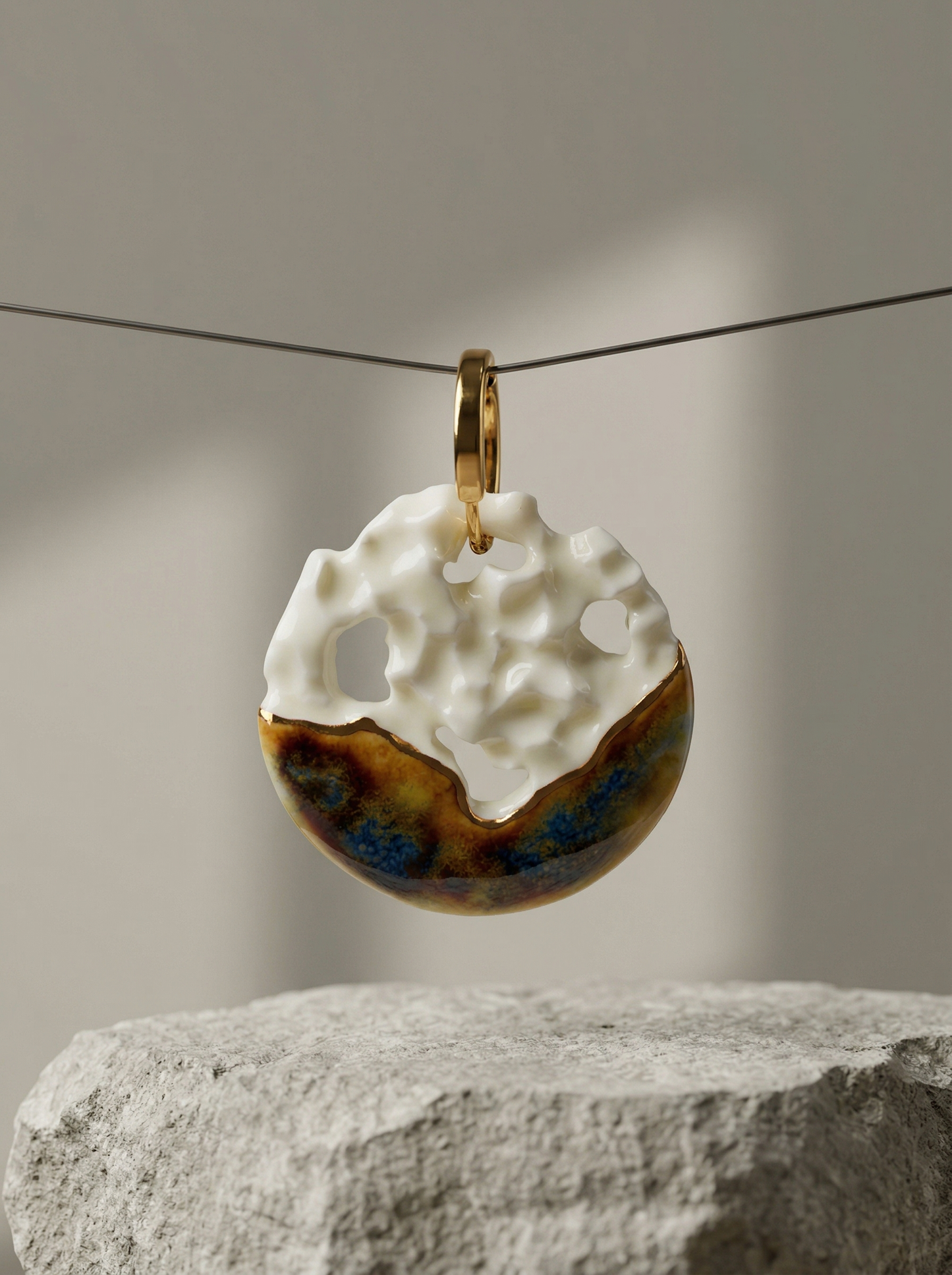 A single handmade ceramic hoop earring featuring white crater-like cutouts and metallic glaze, suspended on a thin wire above a rough grey stone block. HECROWN 1-of-1 wearable art displayed in a minimalist gallery setting, highlighting its architectural design and raw material contrast.