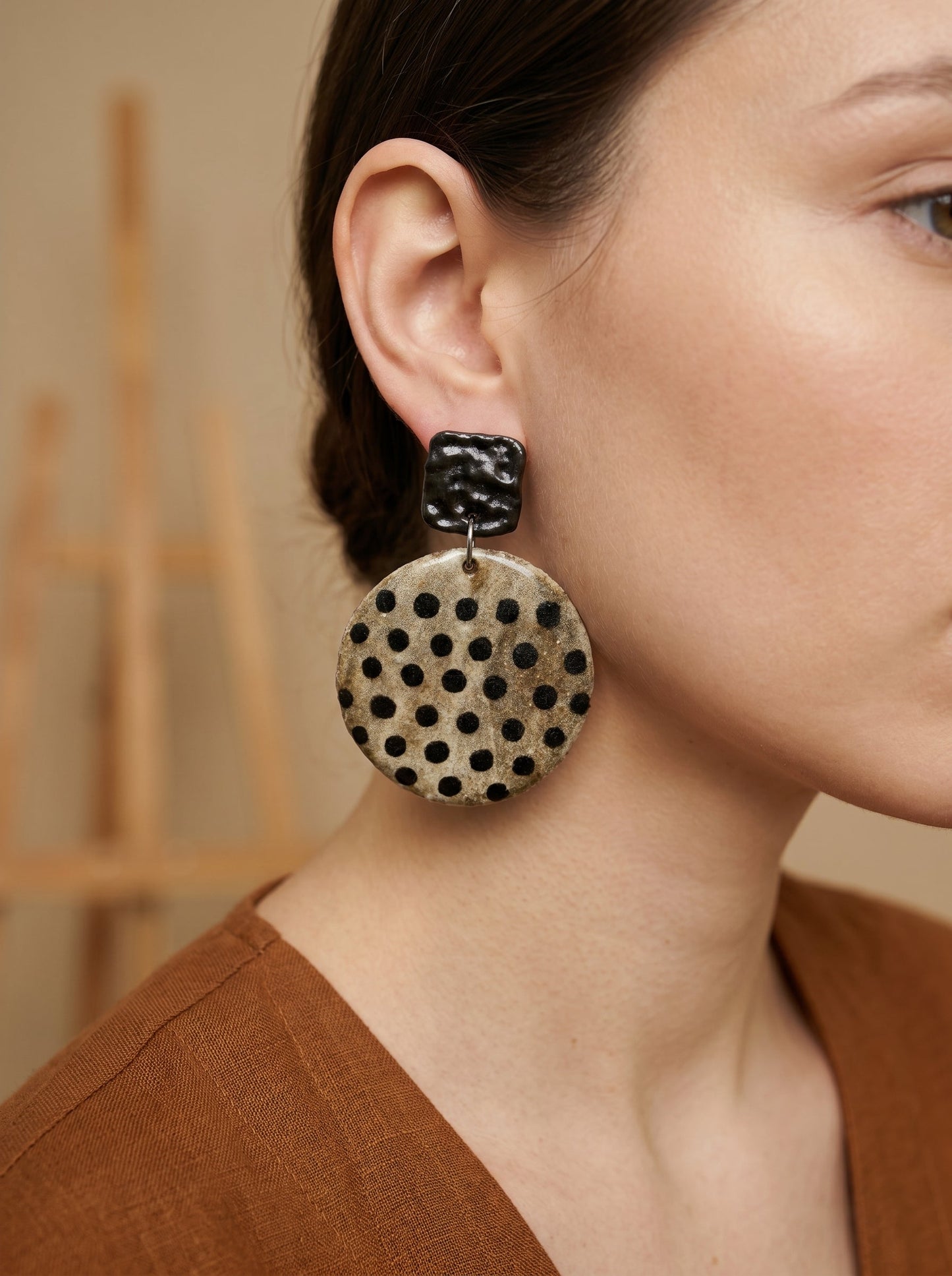 Model wearing HECROWN chunky round ceramic earrings with black speckled dots. A bold yet elegant piece of wearable art, ideal for a unique anniversary gift.