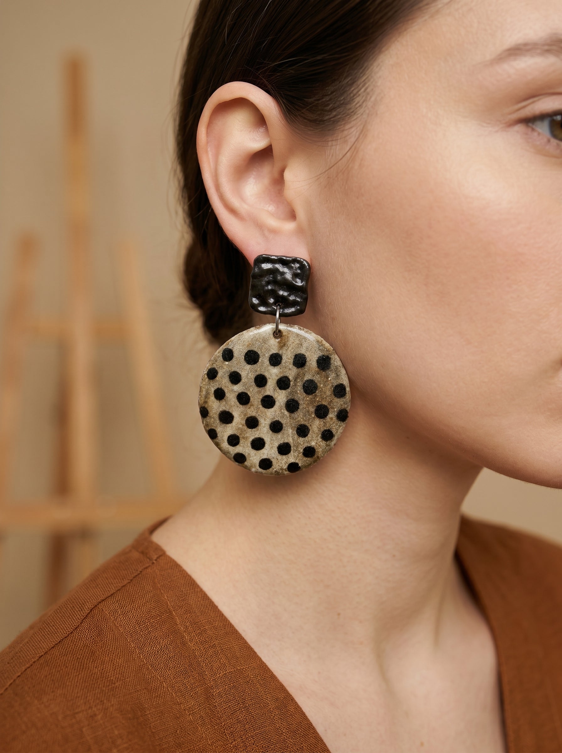 Model wearing HECROWN chunky round ceramic earrings with black speckled dots. A bold yet elegant piece of wearable art, ideal for a unique anniversary gift.