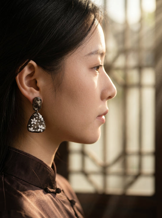 Side profile of a model wearing HECROWN chunky round ceramic earrings with black speckled dots. A bold piece of wearable art highlighting sincere Jingdezhen craftsmanship.