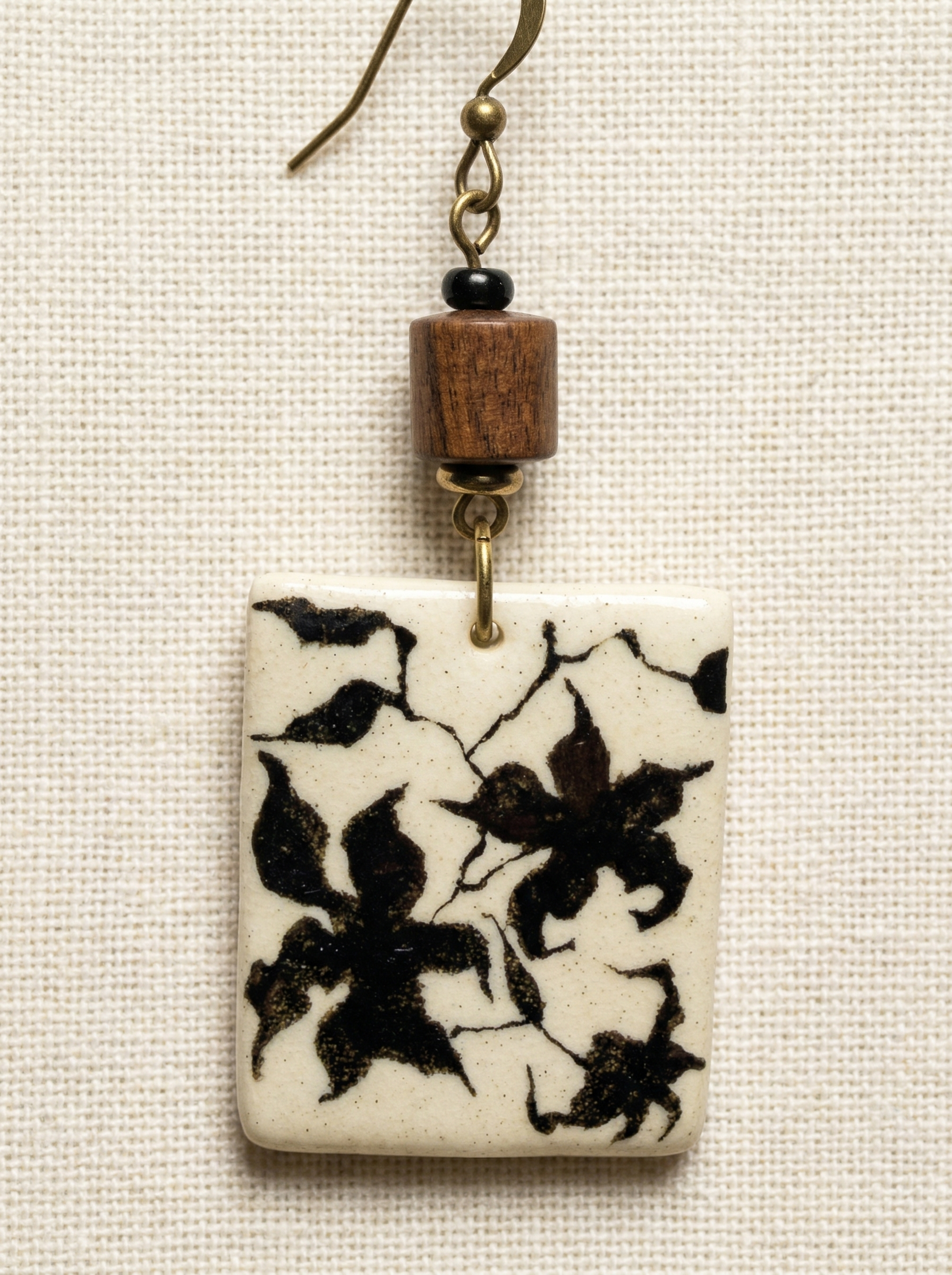 Close-up of a HECROWN porcelain earring highlighting the freehand black floral motif, wooden accent, and brass hook. A perfect Valentine's Day gift showcasing sincere Jingdezhen craftsmanship.