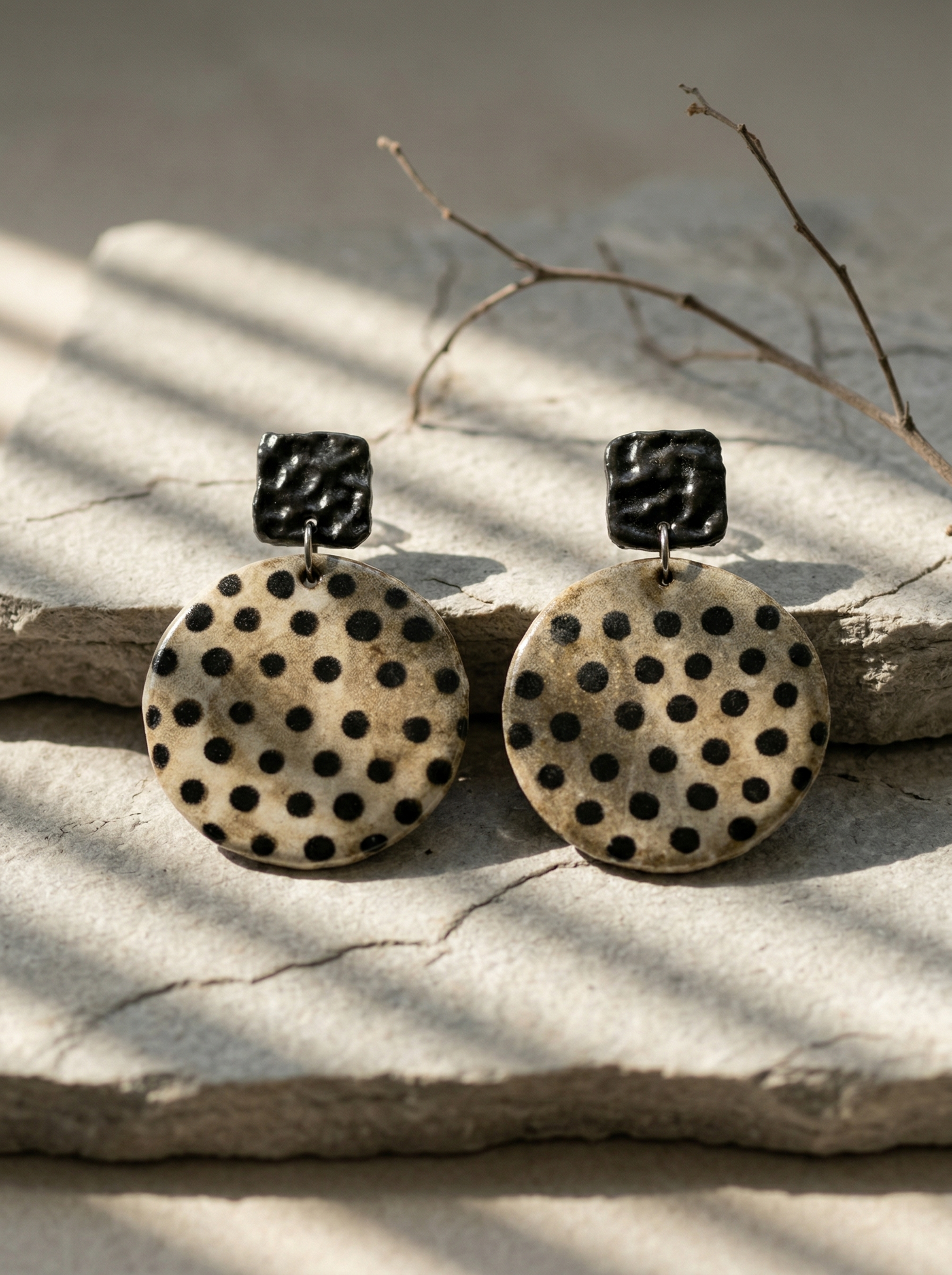 HECROWN round polka dot ceramic earrings resting on a light stone slab under branch shadows. A sincere piece of Jingdezhen ceramic art, perfect as a Valentine's Day gift.