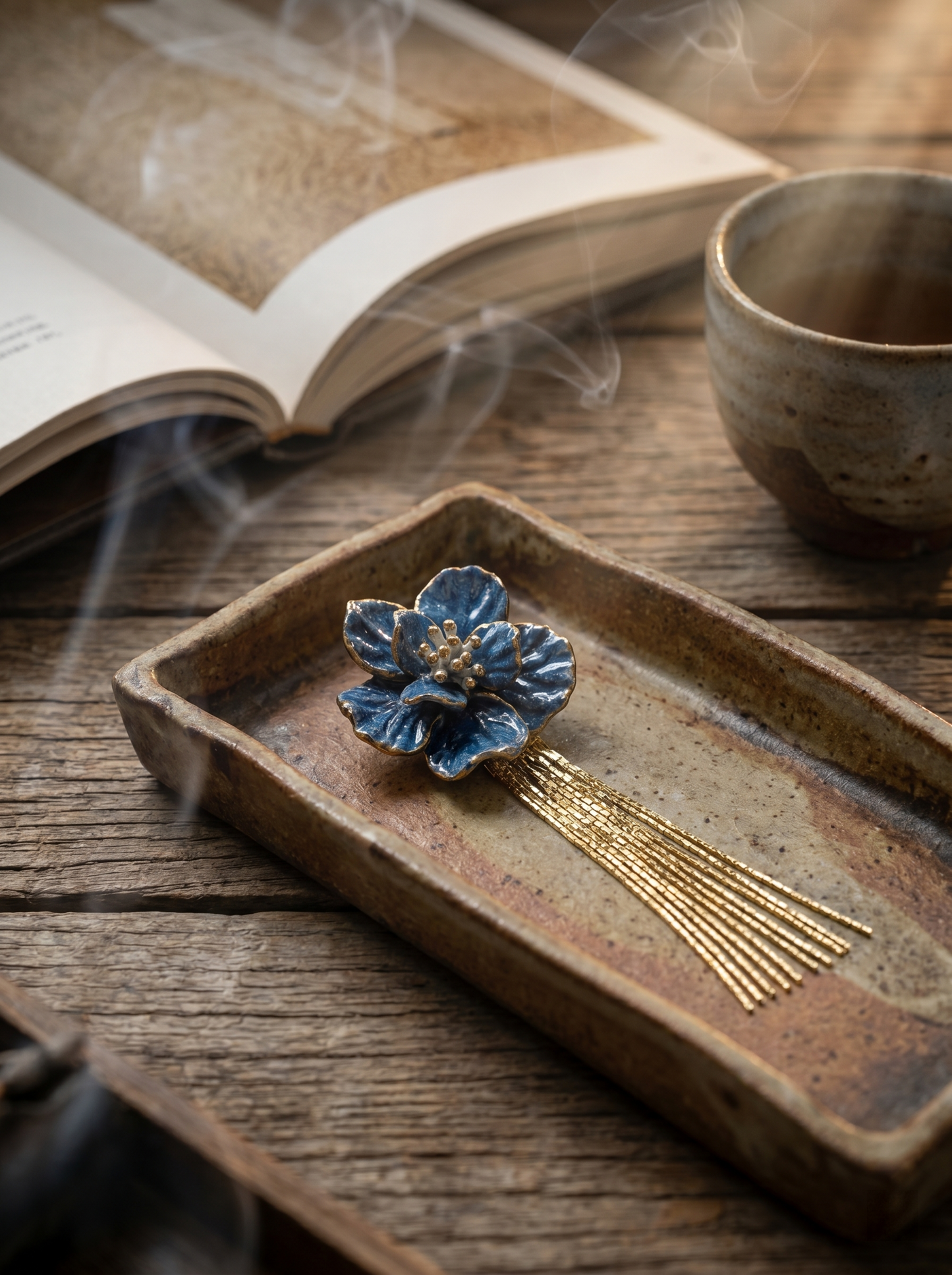 Blue ceramic flower tassel earring in a rustic ceramic tray with incense smoke and tea. Reflecting the Zen aesthetic and sincere focus of Jingdezhen handmade jewelry.